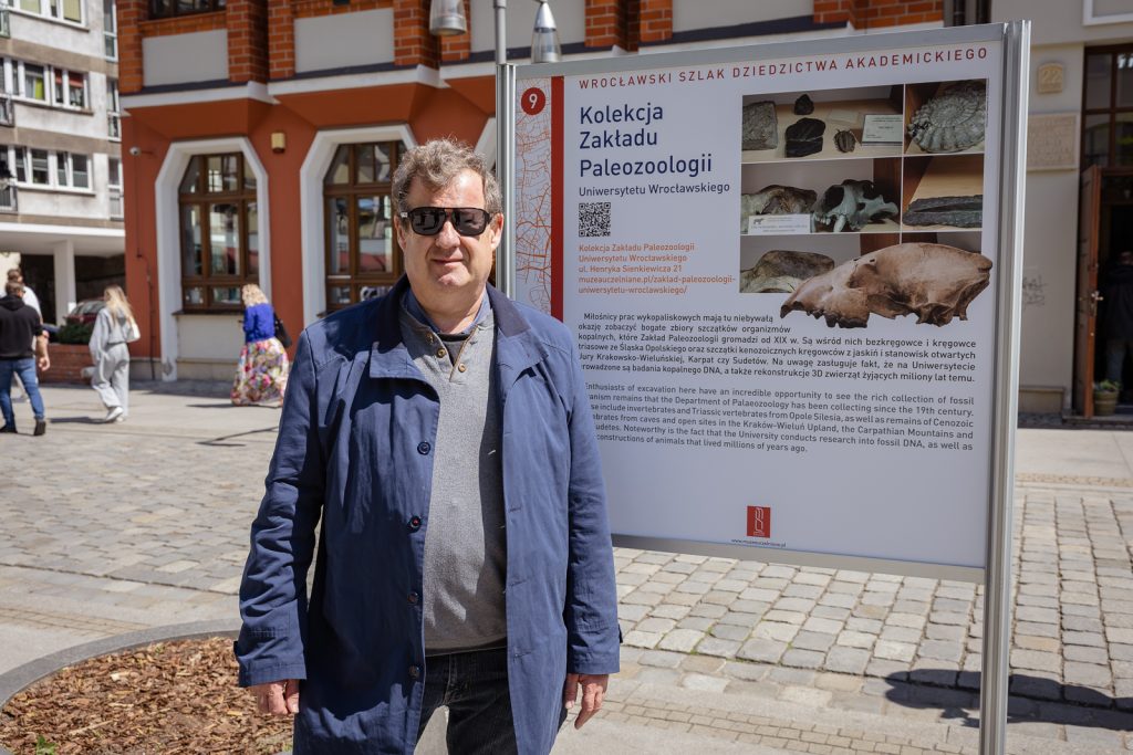 prof. dr hab. Krzysztof Stefaniak obok tablicy informacyjnej o kolekcji Zakładu Paleozoologii UWr